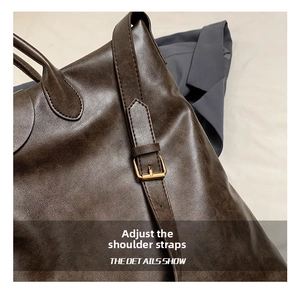 Detail van verstelbare bruine PU-lederen riem met matte gouden gesp aan de tote tas