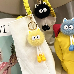 Three colorful plush monster keychains on bags featuring big eyes and cute boots