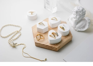 Detailed arrangement of gold rings and pearl necklace on white geometric display stands