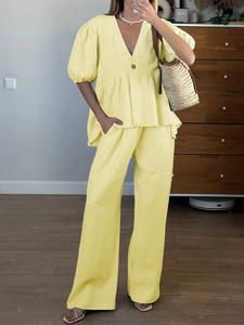 Detail of yellow two-piece linen set featuring V-neck puff sleeve top and wide leg pants
