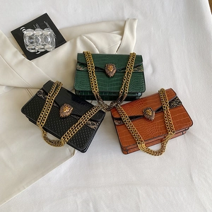 Three crocodile embossed chain bags in green, black, and brown with golden lion buckle