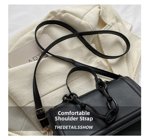 Detail of minimalist black leather crossbody bag with chic chain strap and thin shoulder strap