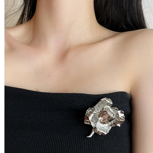 Close-up of a vintage silver rose flower brooch pinned on a black garment for women