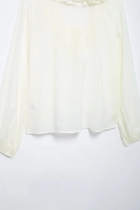 Detailed close-up of white chiffon blouse showing ruffle V-neck and delicate fabric texture