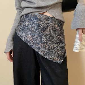 Detailed view of the paisley silk scarf tied as a waist belt on grey knitwear