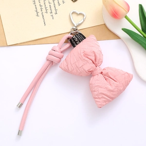 Pink quilted bow keychain with silver heart clasp and matching lanyard on aesthetic desk