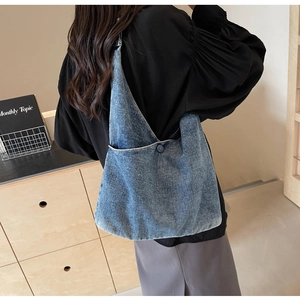 Detail of blue denim tote bag showing minimalist design and decorative button feature