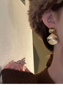 Gros plan de boucles d'oreilles dorées rondes et de bagues argentées sur un mannequin