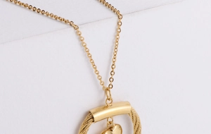 Detailed close-up of golden heart pendant with elegant woven cable texture design