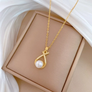 Close-up of gold pearl necklace with diamond-encrusted cross pendant on a jewelry box
