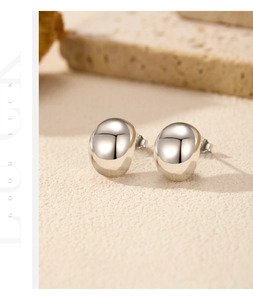Macro detail of silver bean earrings with a mirror-polished finish on a textured stone