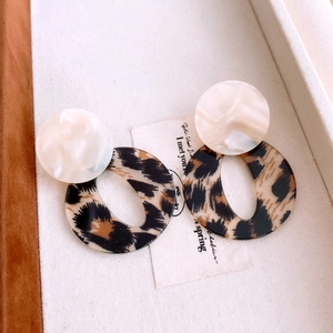 Macro shot of acrylic leopard print oval earrings with white stud in a jewelry box