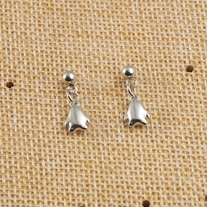 Vue rapprochée de boucles d'oreilles en acier argenté avec breloques pingouins sur jute