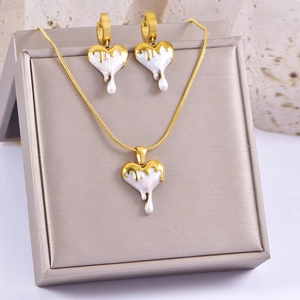 Detail of gold necklace and earrings set with white liquid heart-shaped enamel