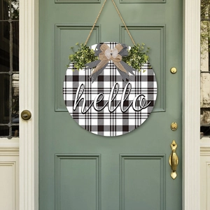 Round wooden Hello sign with buffalo plaid pattern and greenery for front door decor