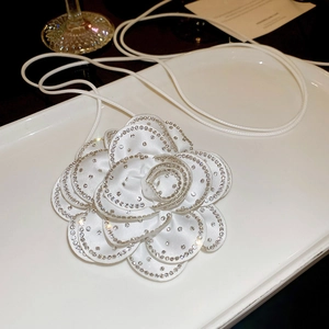 Détail d'un collier fleur de camélia en satin blanc avec cristaux scintillants