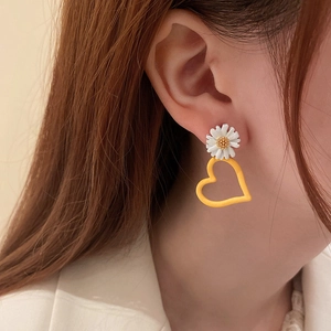 Sweet asymmetric daisy and hollow heart earrings shown on a model for a fresh look