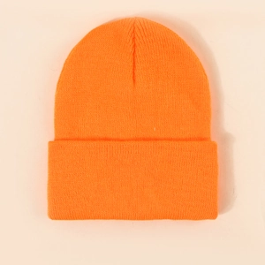 Detailed view of the fine ribbed knit texture on a bright orange folded beanie hat