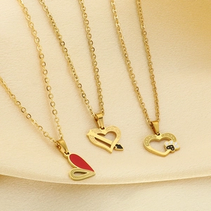 Détail de colliers en acier inoxydable doré avec pendentifs cœur en émail sur du satin