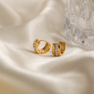 Dettaglio di orecchini a cerchio spessi in oro 18K con zirconi bianchi quadrati su seta