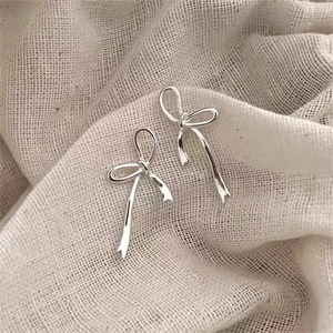 Minimalist 925 sterling silver bow knot stud earrings on a natural linen background