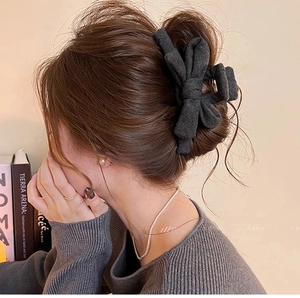 Détail d'une pince à cheveux avec nœud en tissu gris foncé sur un chignon élégant