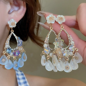 Macro detail of luxury floral tassel earrings with rhinestones and pearl resin drops