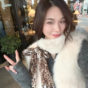 Close-up of white faux fur scarf with a leopard print silk bow and soft texture
