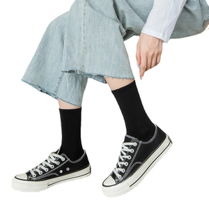 Classic black crew socks for men and women styled with denim jeans and canvas shoes