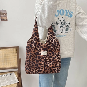 Leopard print canvas tote bag with white woven label on model in minimalist setting