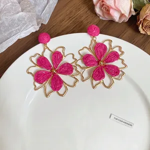 Exquisite fuchsiafarbene Raffia-Hohlblüten-Ohrringe mit Goldmetallrahmen in weißer Schale