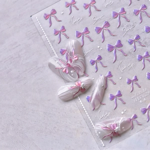 Détail de stickers 3D pour ongles avec nœuds œil-de-chat roses et accents de perles