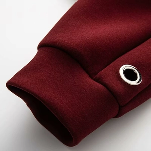 Gros plan du tissu de sweat-shirt rouge foncé montrant la couture et l'œillet métallique