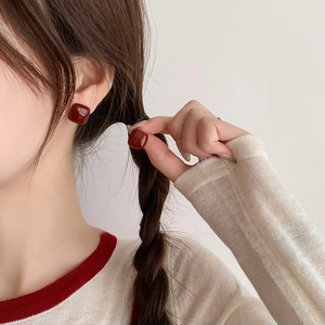 Primo piano della modella con orecchini quadrati in resina rossa dal design vintage