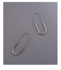 Detailed view of silver U-shaped safety pin earrings with polished metallic finish
