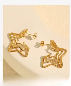 Close-up of triple-layered hollow star earrings in glossy gold finish on stone
