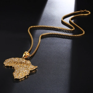 Detail of gold Africa map pendant encrusted with sparkling rhinestones on black background