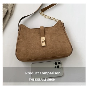 Detail of suede crossbody bag with gold rectangular clasp and curved cat-ear top edge
