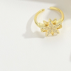 Detail of a gold open ring with a sparkling star motif and inlaid cubic zirconia stones