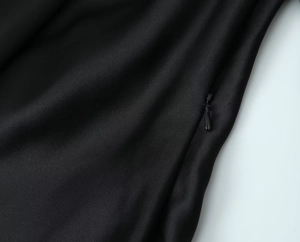 Detailaufnahme des verdeckten Reißverschlusses und der schwarzen Stoffstruktur des Kleides