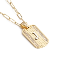 Détail du pendentif rectangulaire doré avec lettre J et chaîne à trombone chic