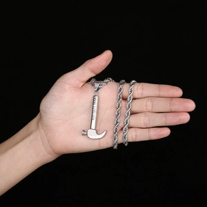 Detailed view of silver hammer pendant on a twisted chain held in a palm over black background