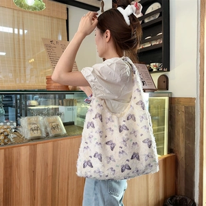 Close-up of a large off-white tote bag with purple butterfly print in a warm cafe