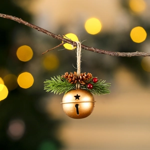 Détail d'une cloche de Noël dorée avec pommes de pin et baies rouges sur un sapin