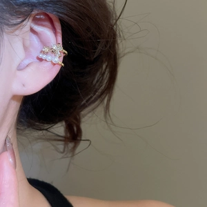Gros plan d'un ear cuff doré double couche avec nœud en zircon et quatre perles