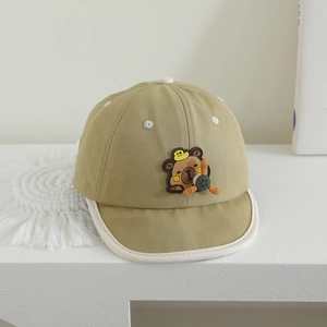 Detail of baby cotton cap featuring a cartoon bear pilot patch and white trim edge