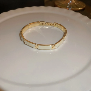 Detail of gold-plated link bracelet featuring white rectangular cat's eye stone insets