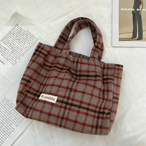Detailed macro view of high-quality wool plaid texture and branding on the tote bag