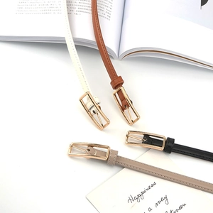 Detail of four thin leather belts with gold rectangular buckles in various colors