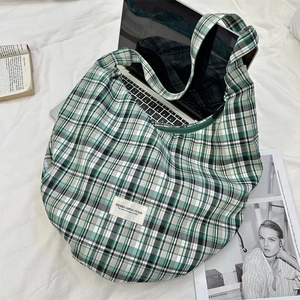 Gros plan du sac fourre-tout à carreaux verts montrant la capacité pour un ordinateur